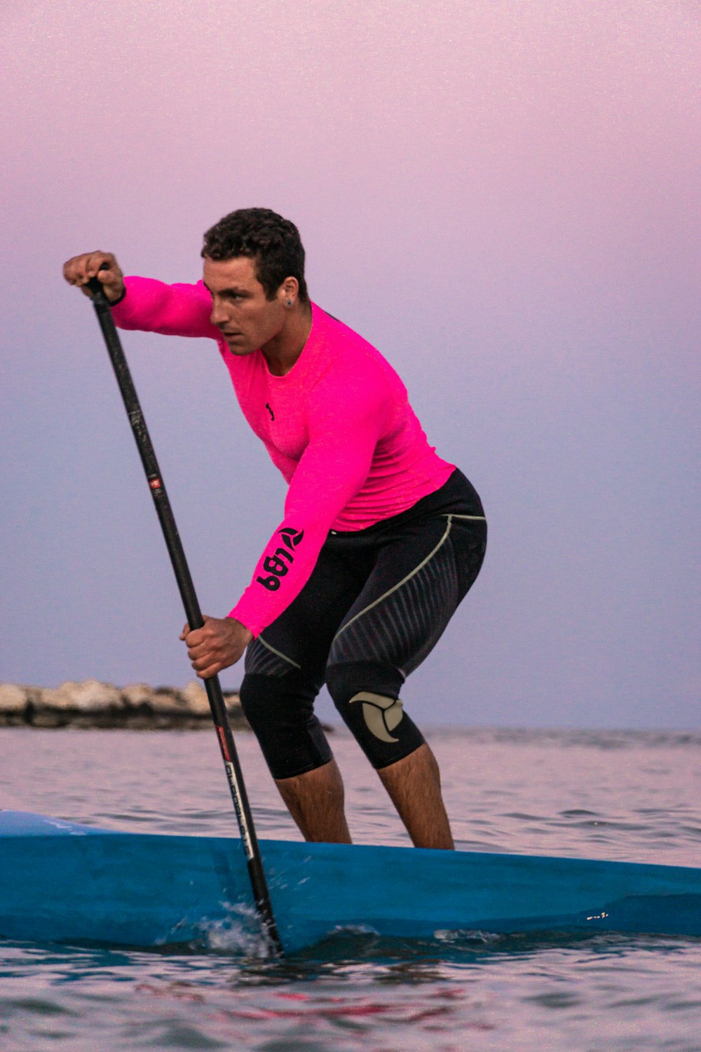 a man in a pink shirt is on a surfboard