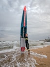 a man holding a surfboard on top of a sandy beach