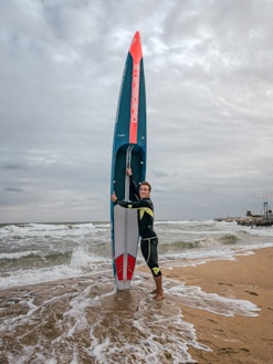 a man holding a surfboard on top of a sandy beach