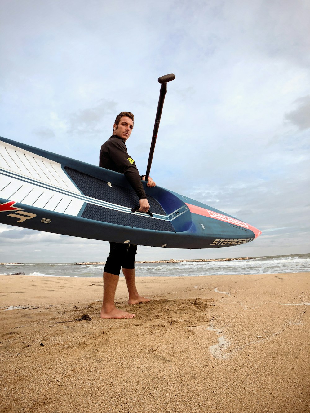 a man holding a paddle board on a beach