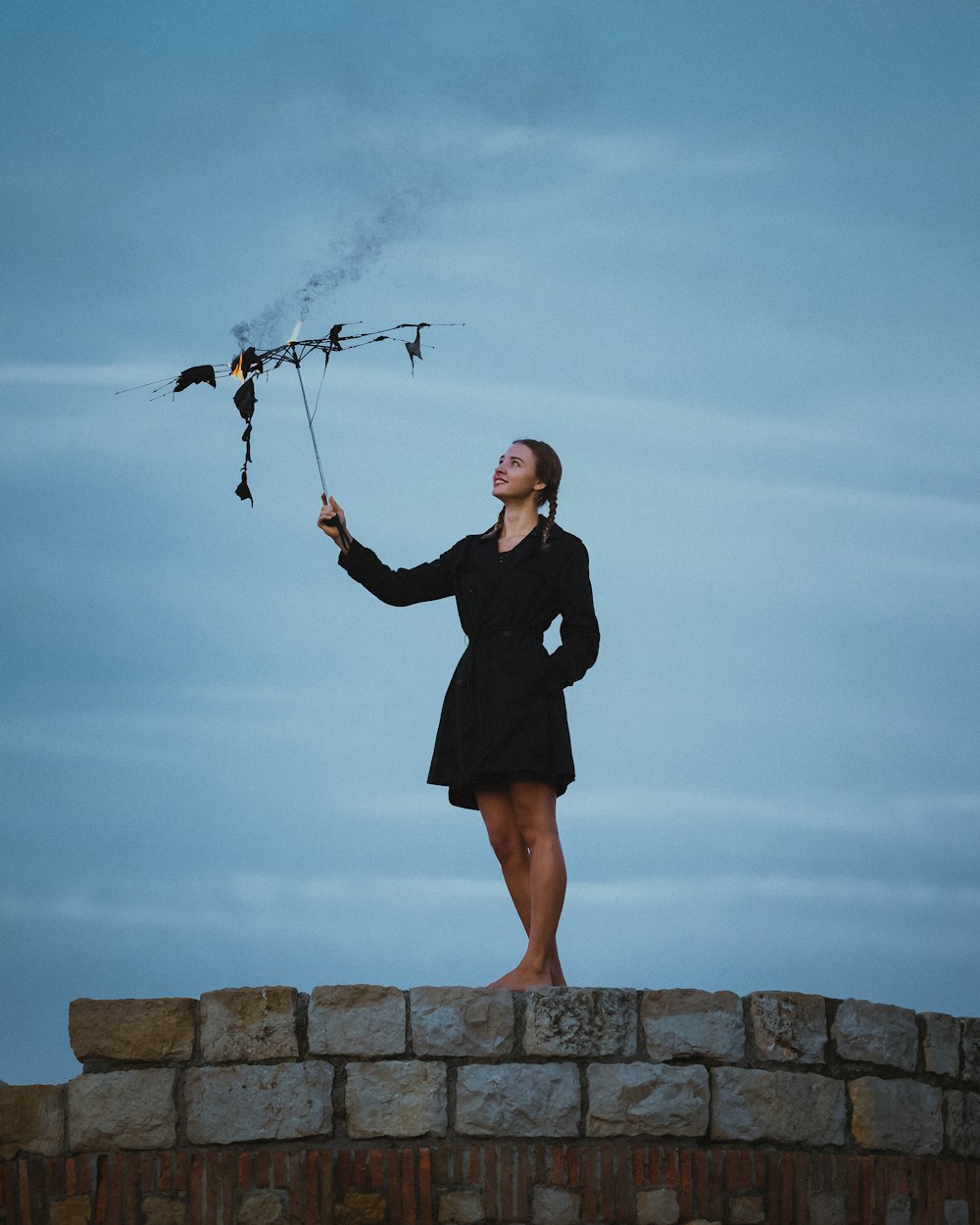 a woman in a black dress holding a kite