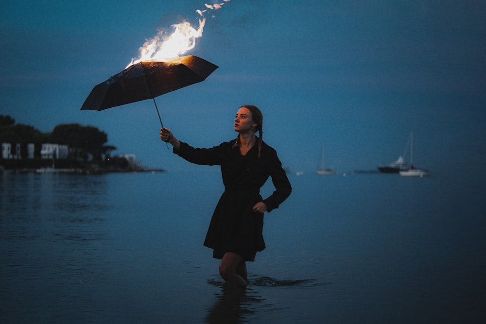 a woman standing in the water holding an umbrella