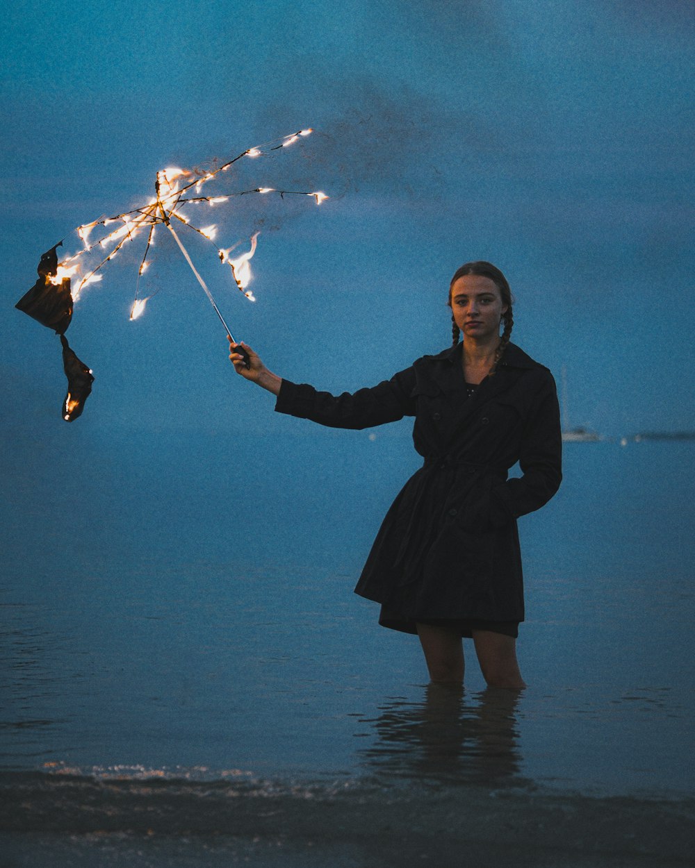 a woman standing in the water holding a sparkler