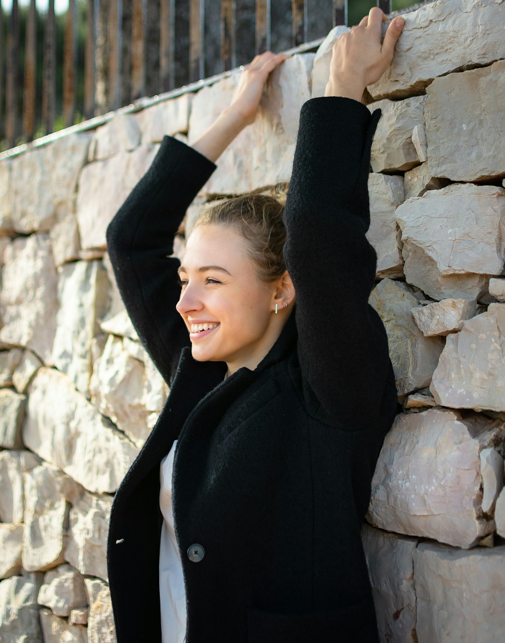 a woman standing next to a stone wall
