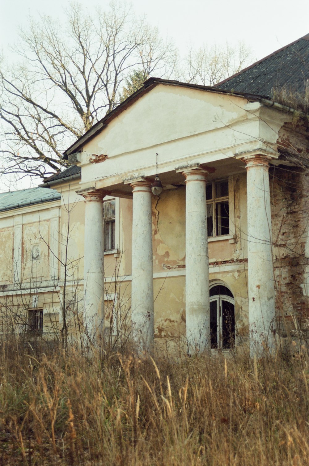 an old abandoned building with columns and a door