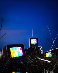 three televisions sitting on top of a pile of grass
