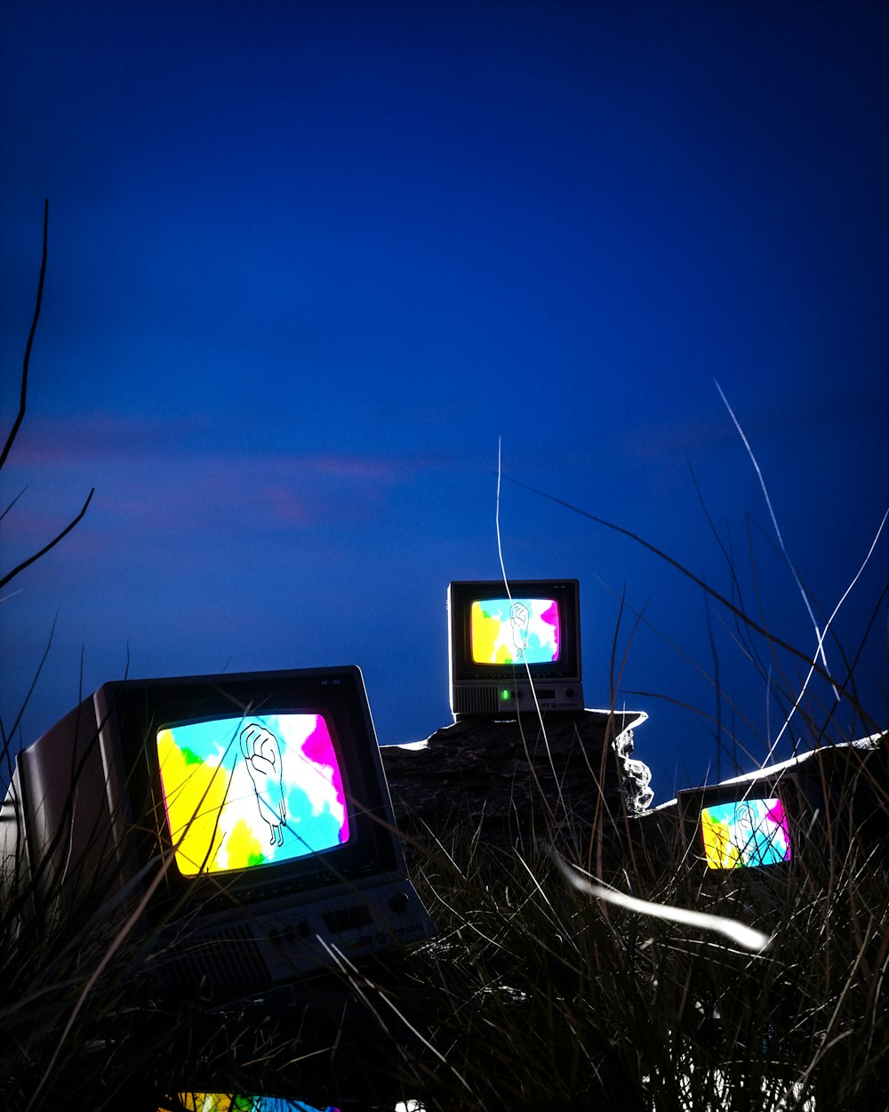 three televisions sitting on top of a pile of grass