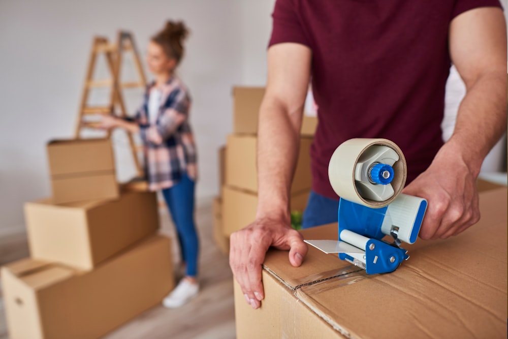 a man and woman moving boxes with a blue roller