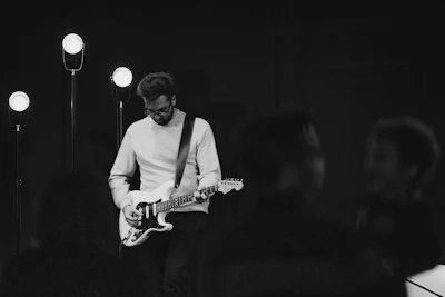 Close-up of a musician playing an electric guitar under stage lights.
