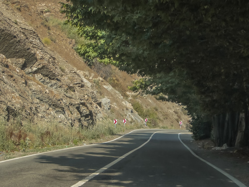 a car driving down a road next to a mountain