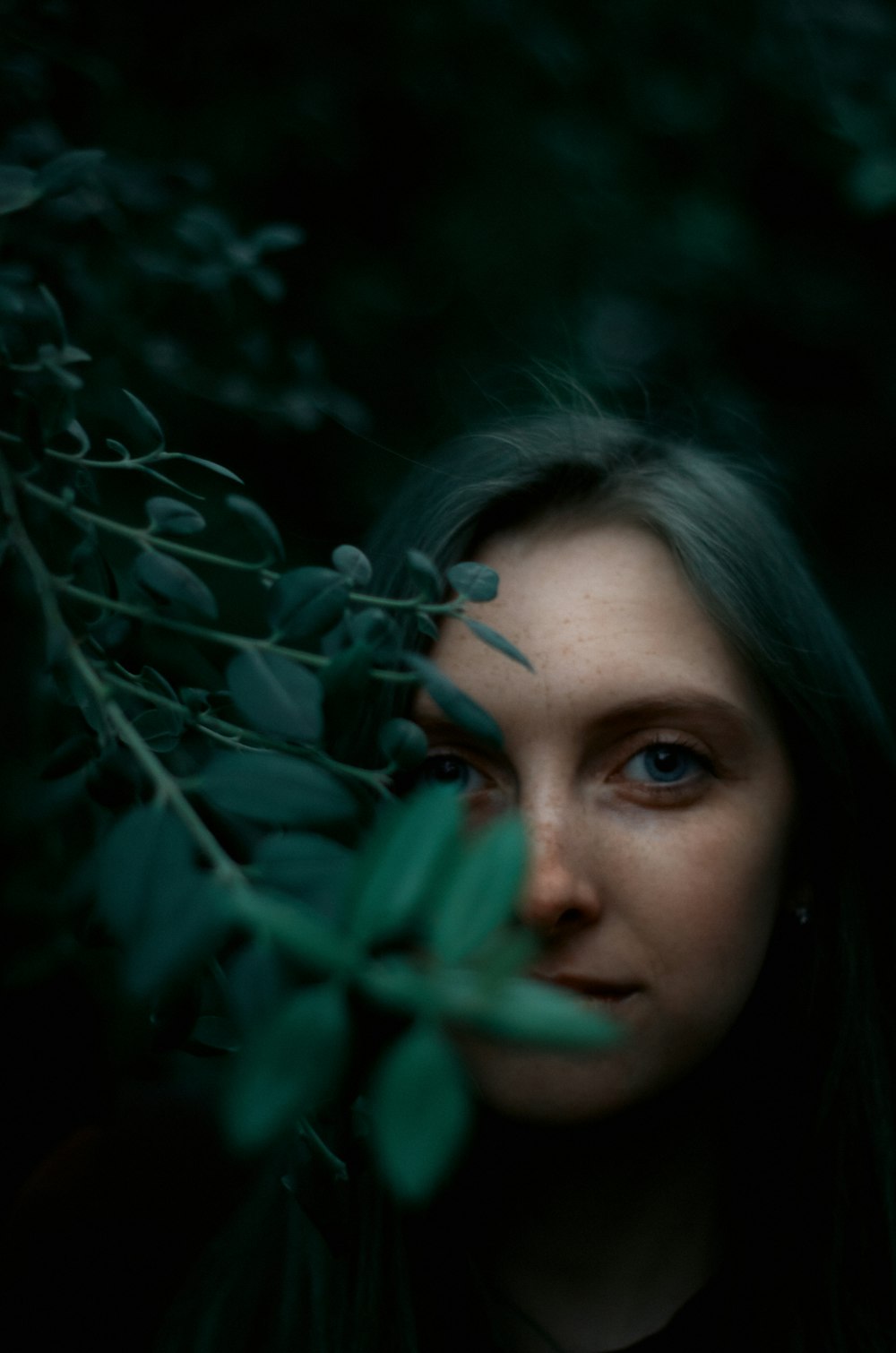 a woman standing in front of a bush with leaves