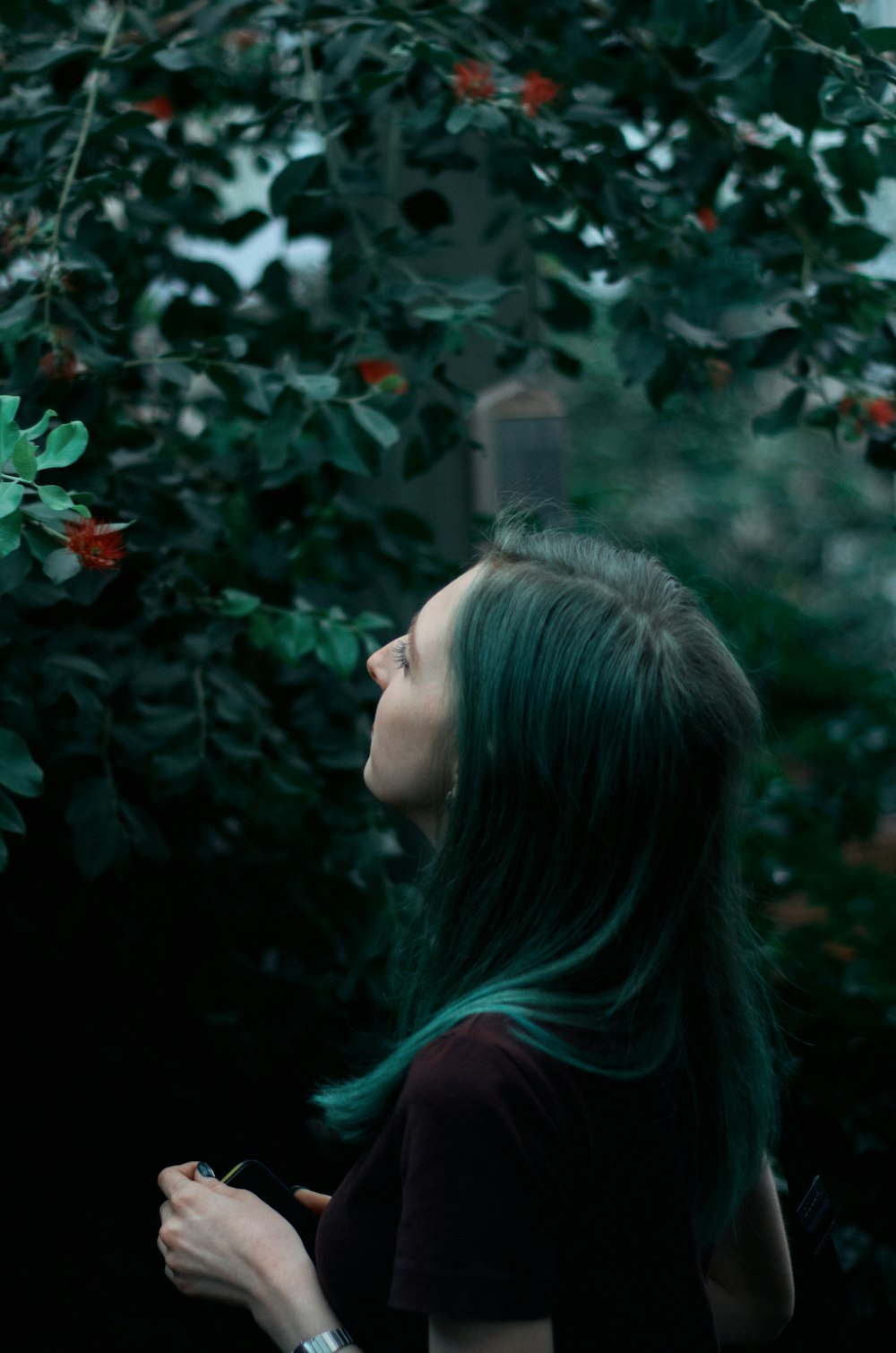 a woman with green hair standing in front of a tree