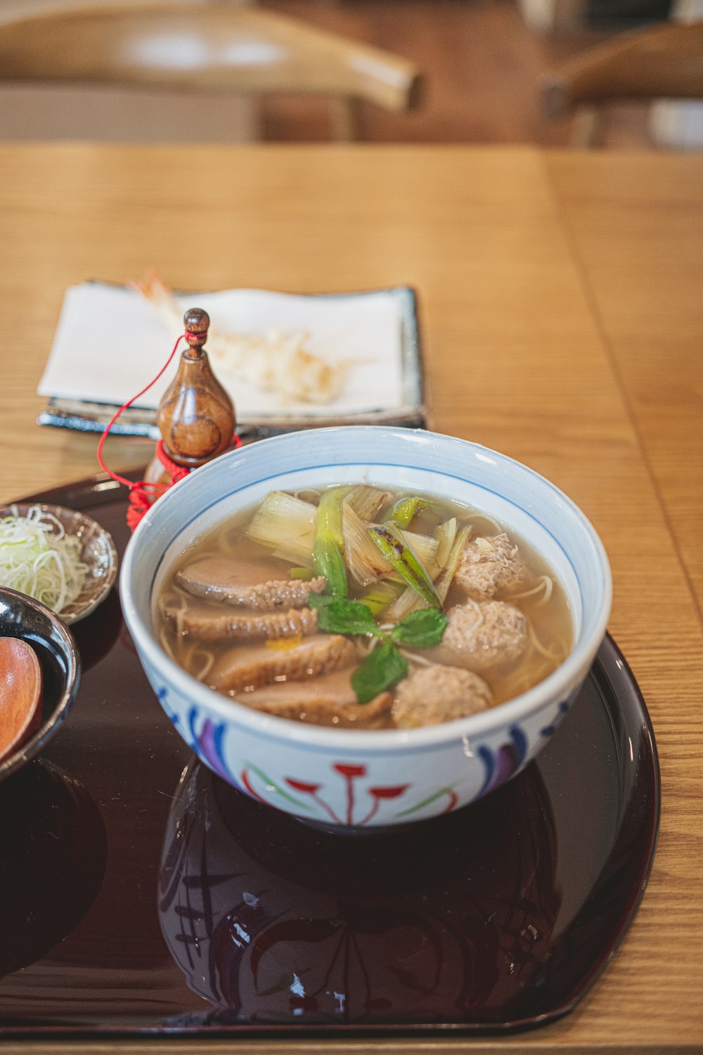 a wooden table topped with a bowl of soup