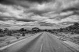 An abandoned rural road stretching into the distance under a brooding sky.
