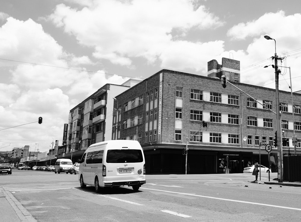 a white bus driving down a street next to tall buildings