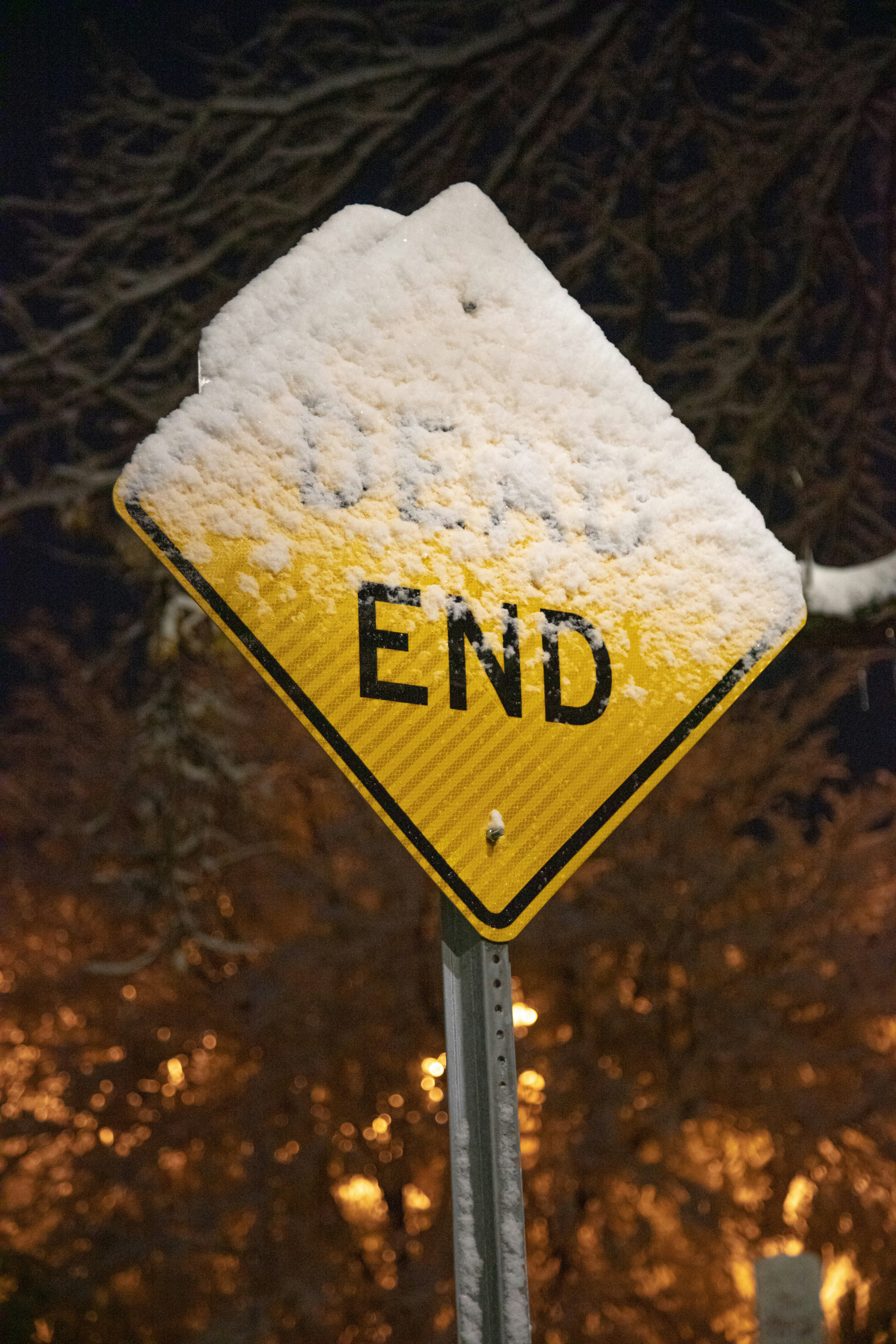 ein gelb-schwarzes Endschild mit Schnee bedeckt