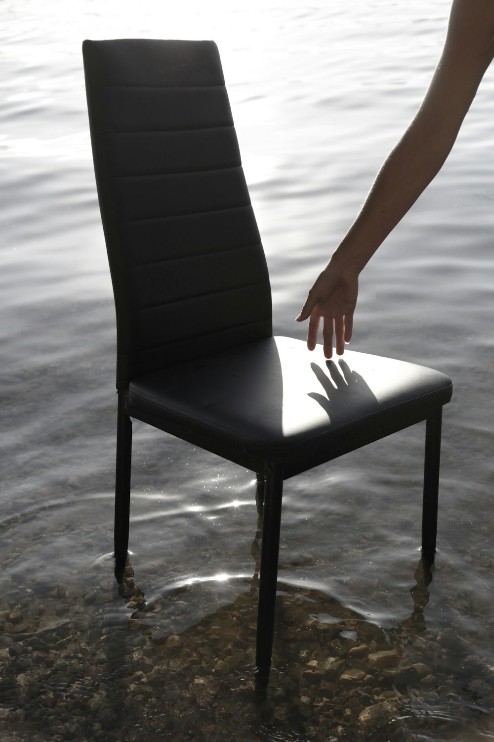 a person reaching for a chair in the water
