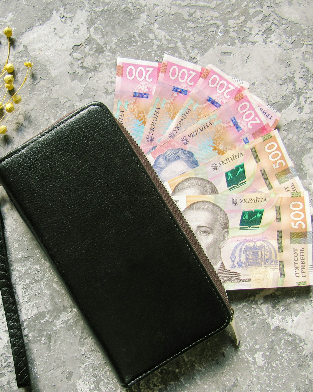 お金の束の隣のテーブルの上に座っている黒い財布