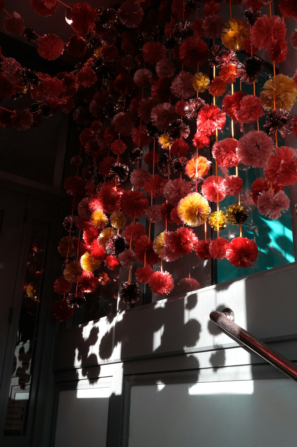 a bunch of red and yellow flowers hanging from a ceiling