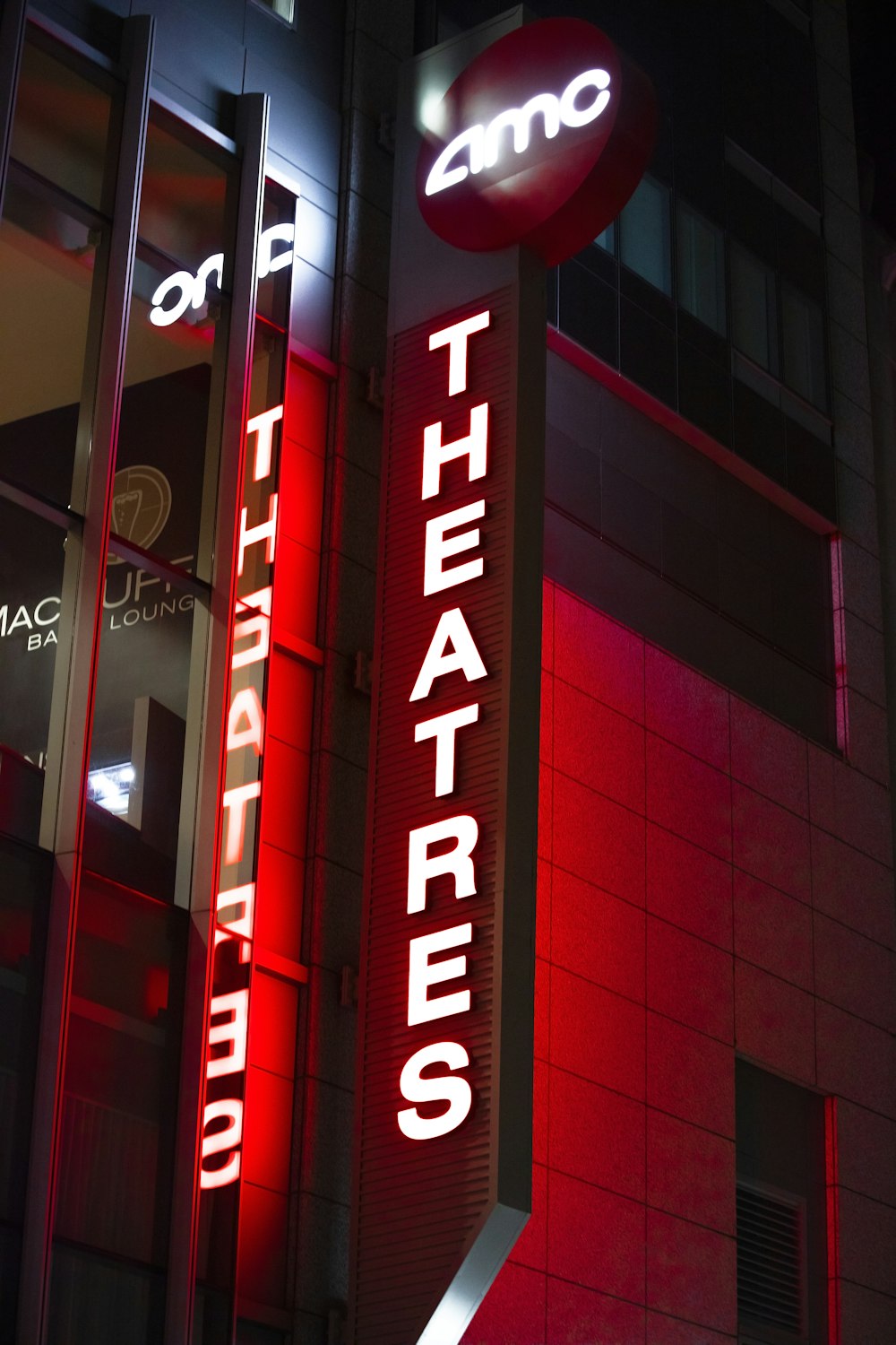 uma placa de teatro iluminada à noite em frente a um edifício