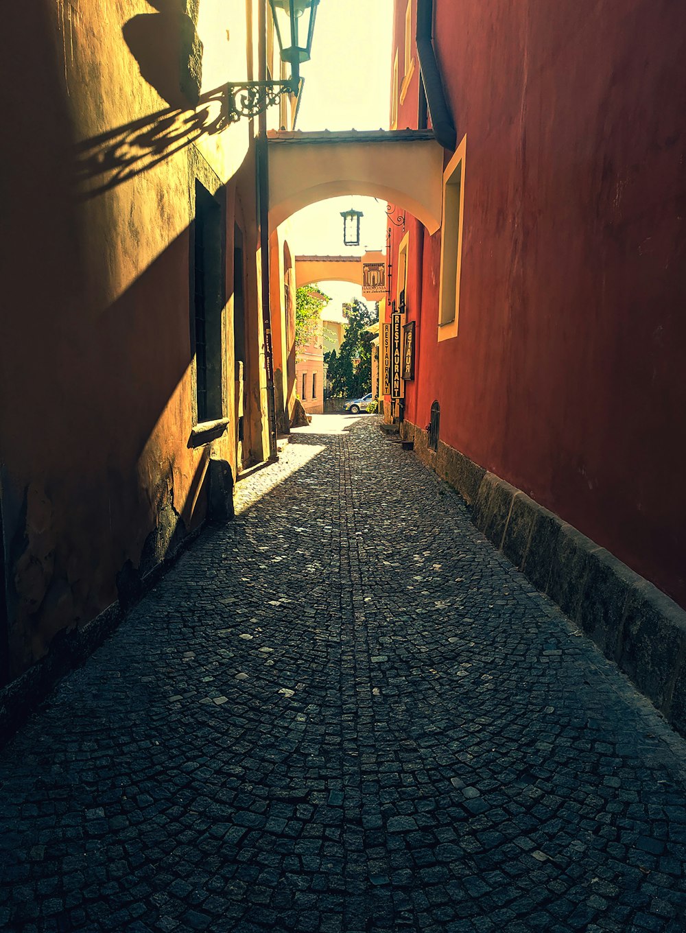 a narrow cobblestone street with a lamp post in the distance