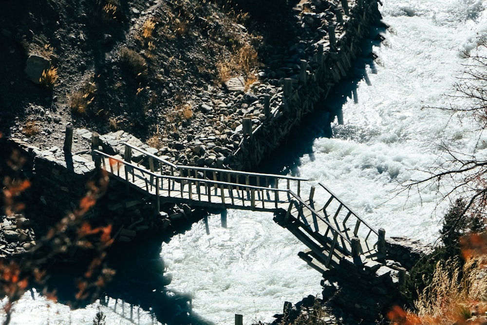 a wooden bridge over a rushing river next to a forest