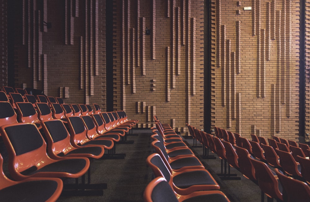 a row of orange chairs in front of a brick wall