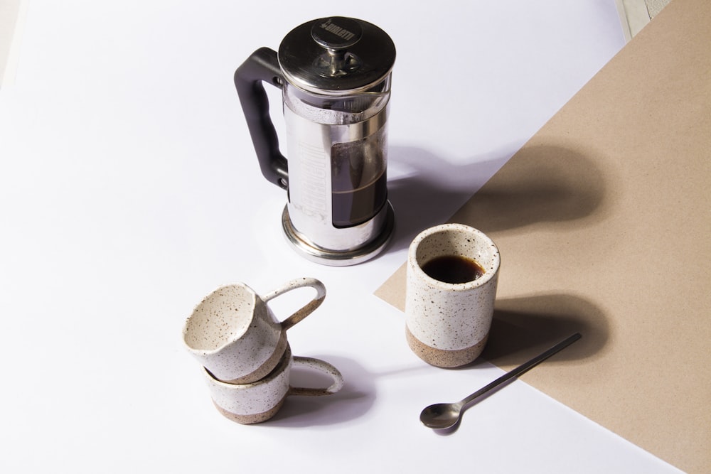 a coffee pot and two mugs on a table