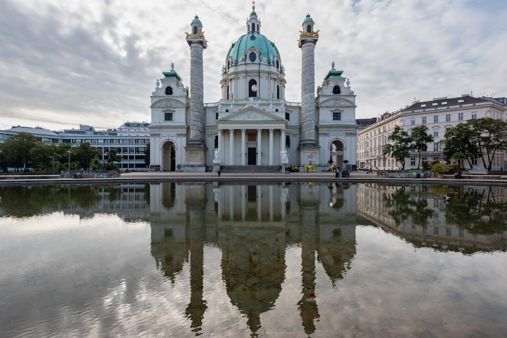 a large white building with a green dome next to a body of water