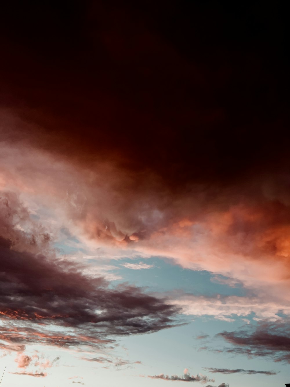 a plane flying through a cloudy sky at sunset