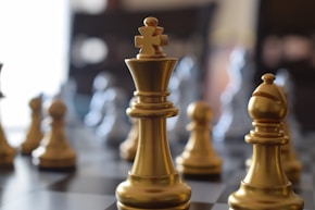 a close up of a chess board with gold pieces