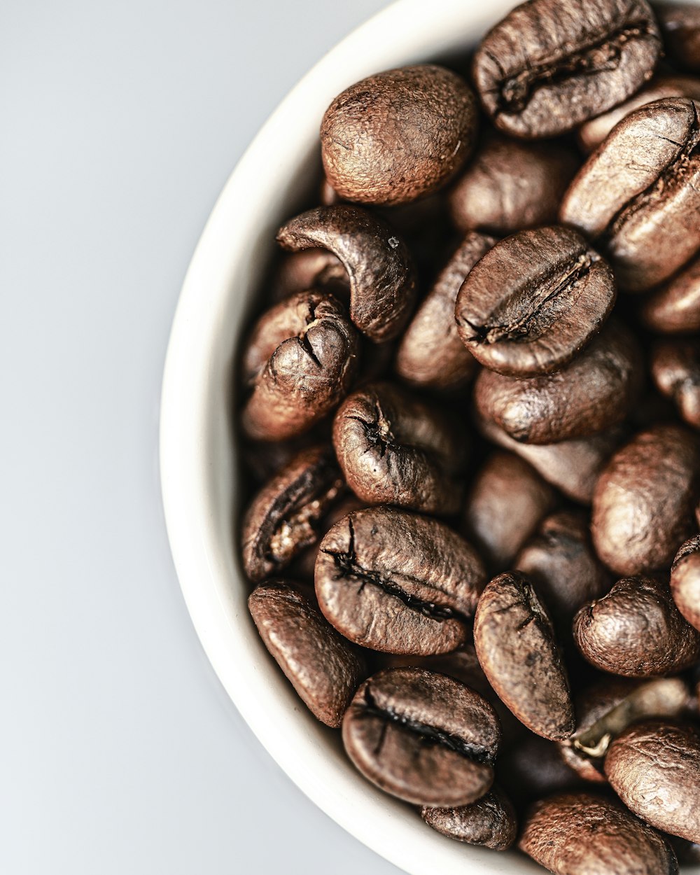 a white bowl filled with coffee beans on top of a table