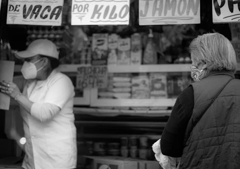 A handshake between a Spanish food producer and an international buyer in a bright marketplace.