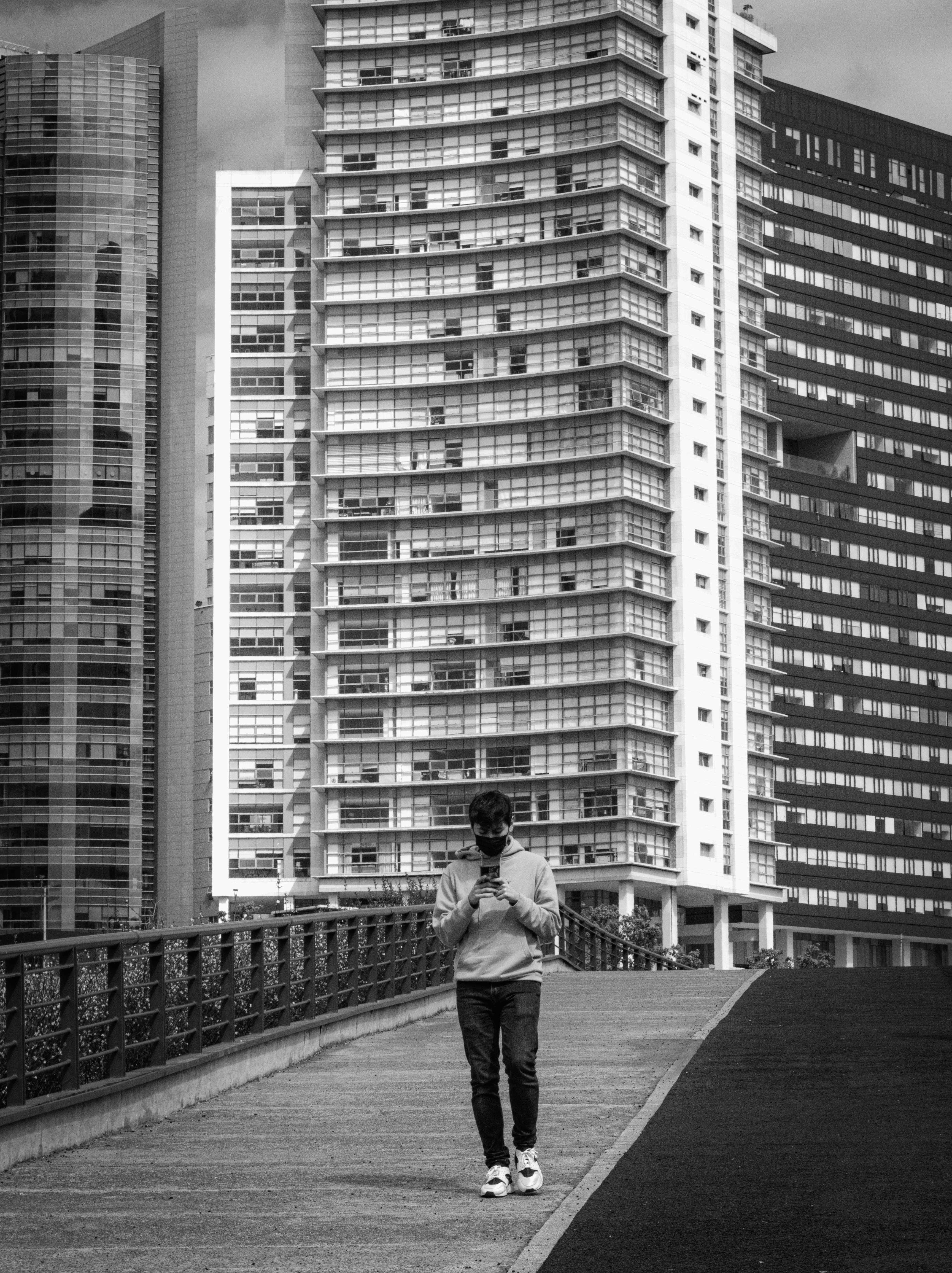 a woman walking across a bridge next to tall buildings