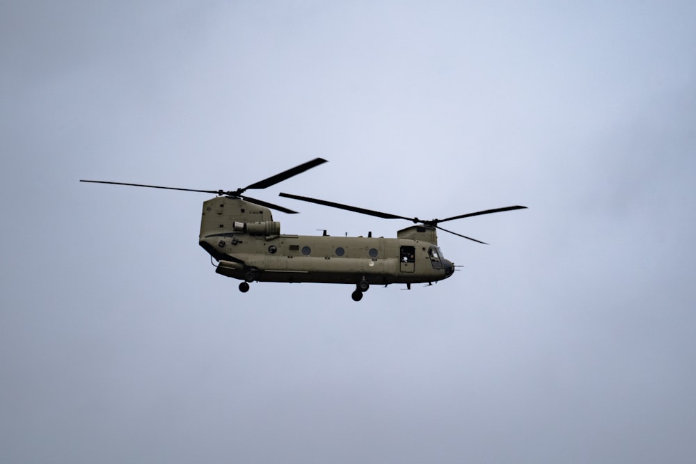 a military helicopter flying through a cloudy sky