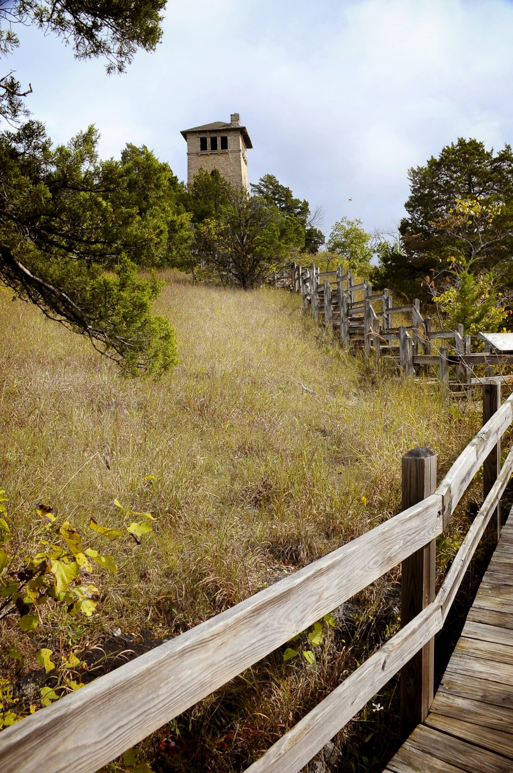 a wooden walkway leading to a tower on a hill