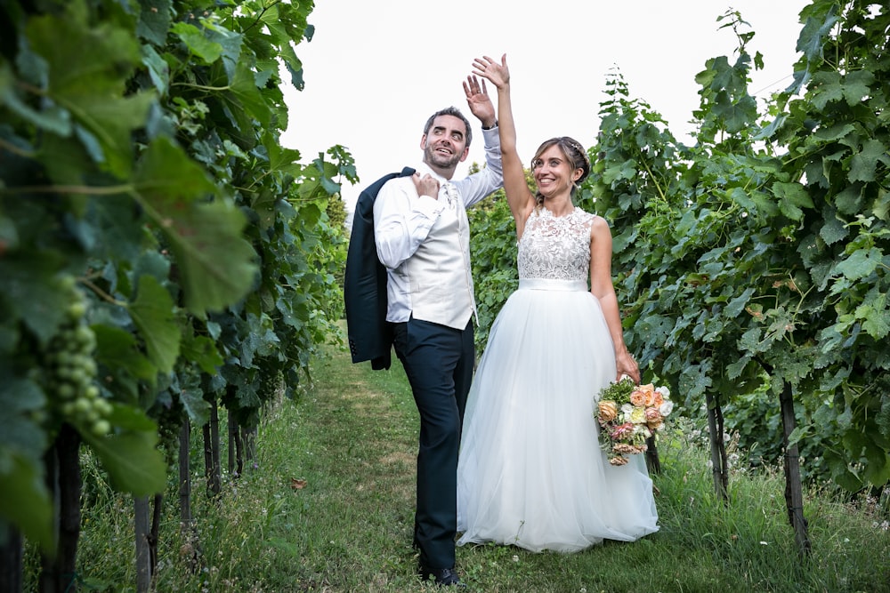 a bride and groom walking through a vineyard