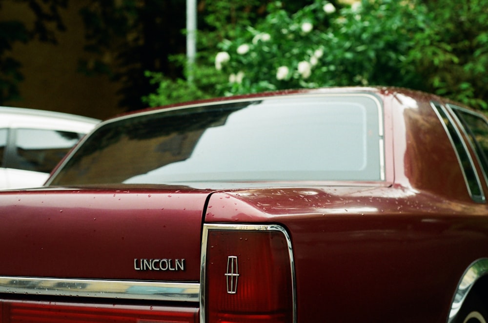 a red lincoln parked in a parking lot