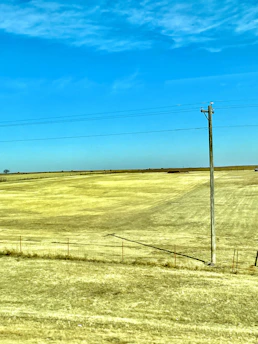 A wide-open country field with clear blue skies and marked property boundaries.
