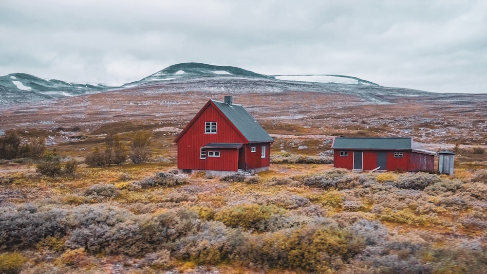 a couple of red buildings sitting on top of a grass covered field