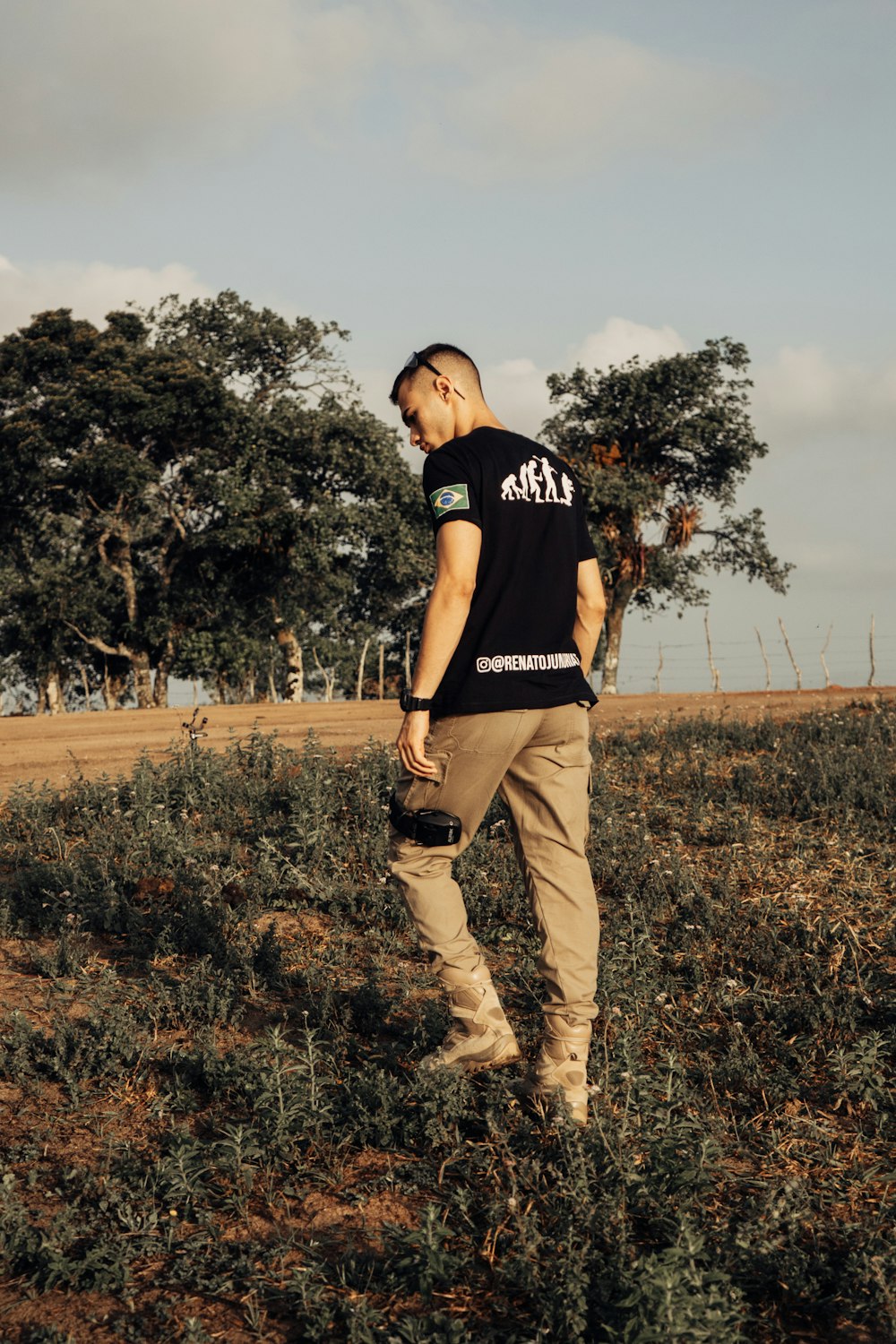 a man standing in a field with trees in the background