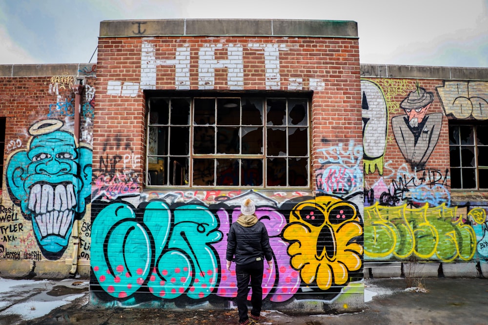 a man standing in front of a graffiti covered building