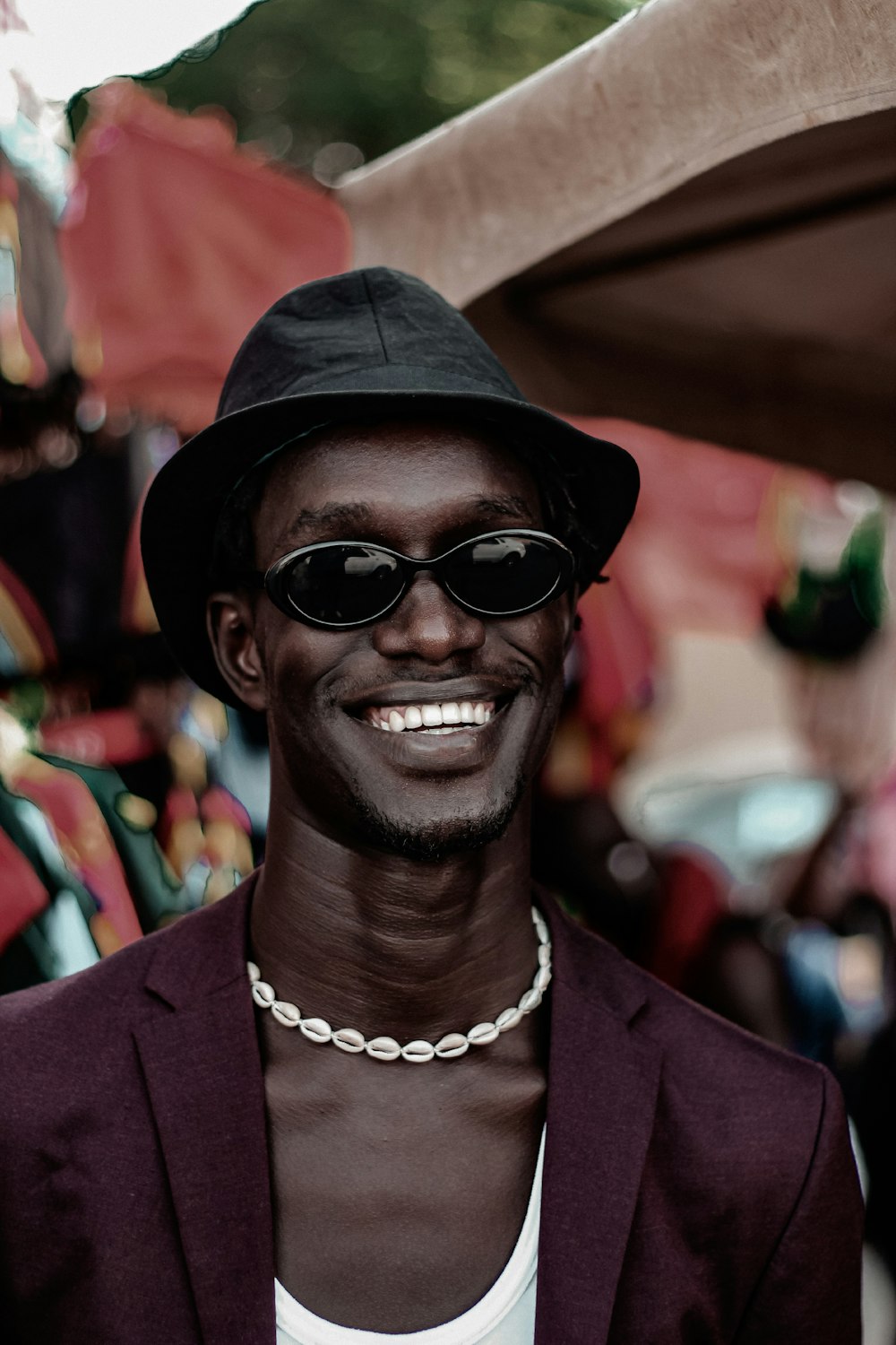 a man in a hat and sunglasses smiles at the camera