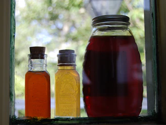 a couple of bottles of liquid sitting on a window sill