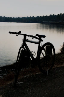 Radit's bicycle parked beside a quiet lakeside at dawn, mist rising off the water.