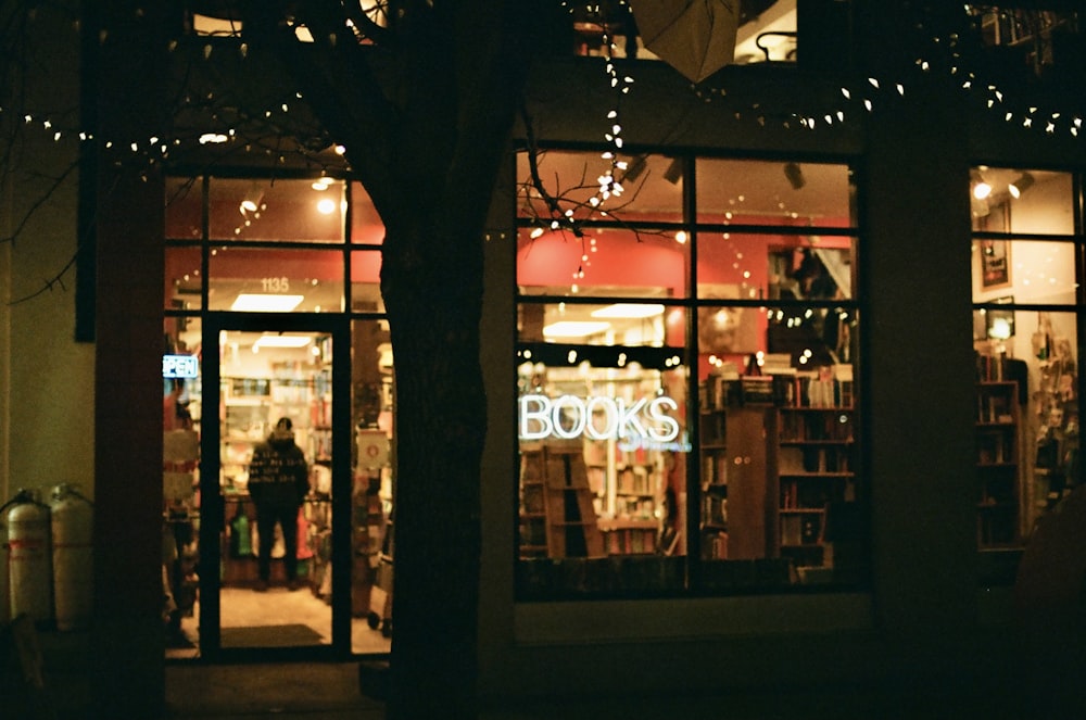 a store front at night with a tree in front of it