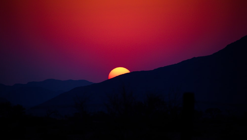 the sun is setting over a mountain range