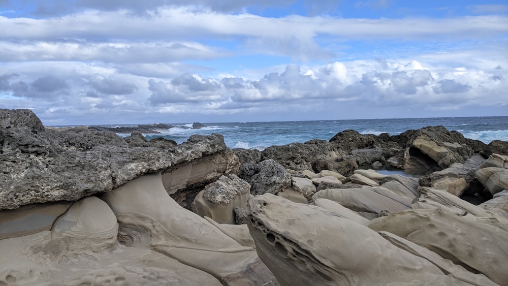 a rock formation on a beach with a body of water in the background