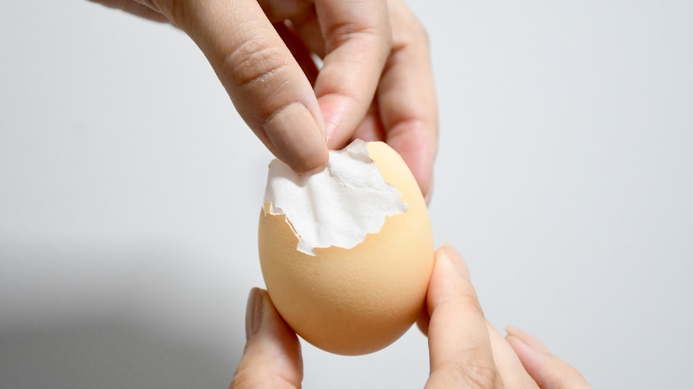 a person holding an egg with whipped cream on it