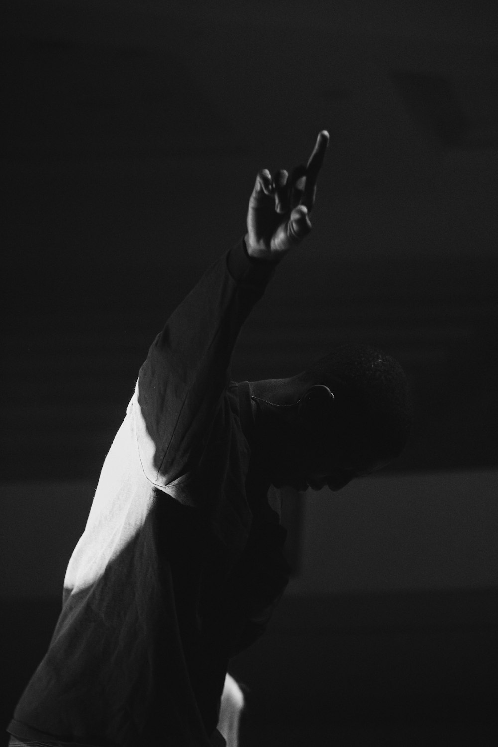 a black and white photo of a person reaching up to catch a frisbee